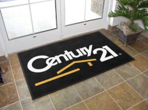 Century 21 branded entrance mat in an indoor doorway (black mat with yellow logo)